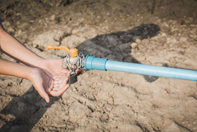 Cropped image of woman with hands cupped under locked faucet