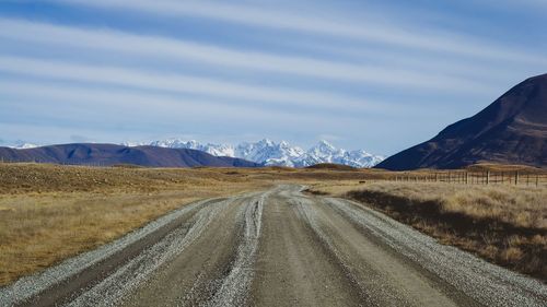 Empty road amidst landscape against sky