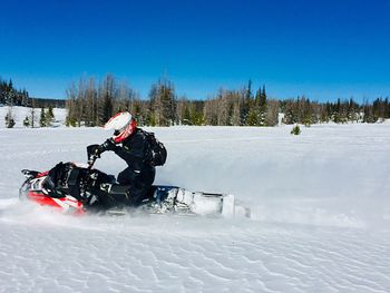 Person riding motorcycle on snow field against sky