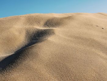 Sand dunes at beach against sky