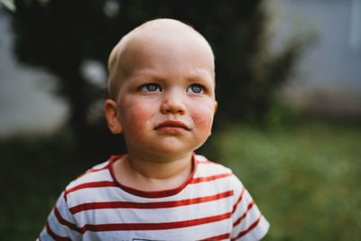 Front view portrait of young boy with serious and dirty face outdoors