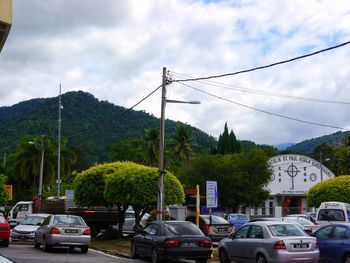 Cars on city street against sky