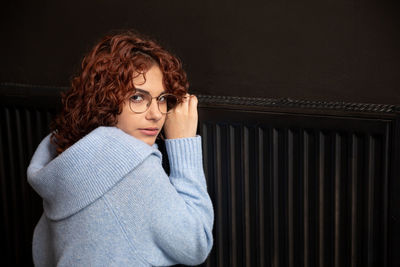 Portrait of young woman standing against wall