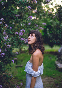 Beautiful young woman standing against tree