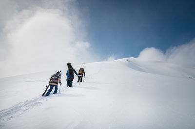 Snowboarder and skier go uphill carrying equipment. off-piste skiing, freeride on a sunny day