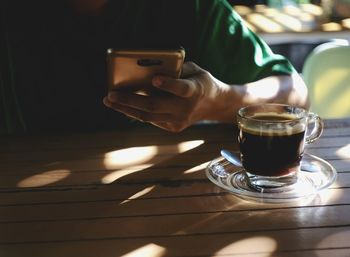 Midsection of man holding coffee cup on table