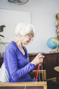 Senior woman knitting while sitting on chair in nursing home