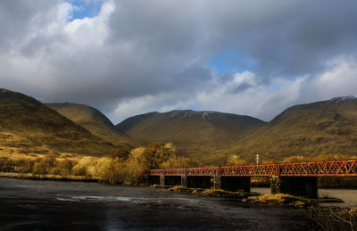 Bridge over river against cloudy sky