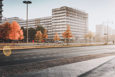 Road by buildings against clear sky