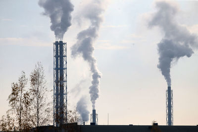 Smoke emitting from factory against sky