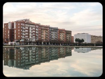Buildings in city against cloudy sky