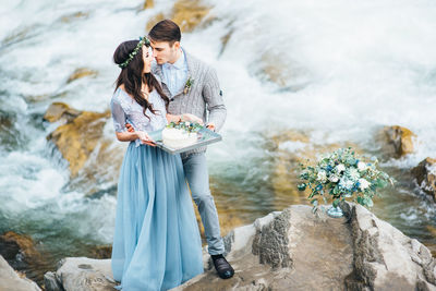 Woman standing on rock by waterfall