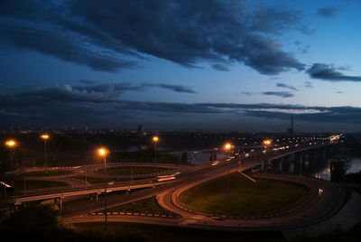 Illuminated multiple lane highway in city against sky during sunset