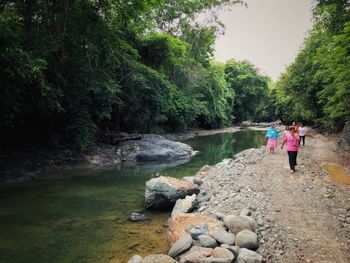 People walking on riverbank against sky