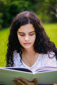 Teenage girl reading book at park