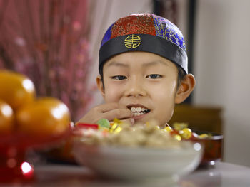 Close-up of boy picking food in container at table