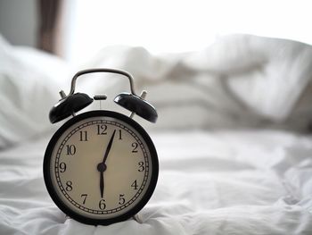 Close-up of clock on bed at home