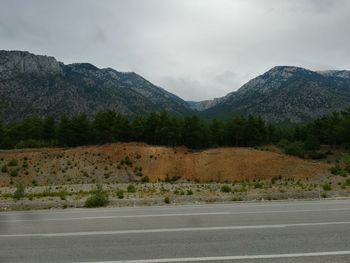 Scenic view of road by mountains against sky