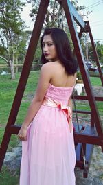 Portrait of beautiful young woman standing against trees