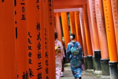 Rear view of women in traditional clothing walking between torii gates