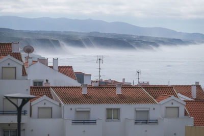 Houses by sea against sky