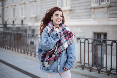 Cheerful woman standing on footpath in city