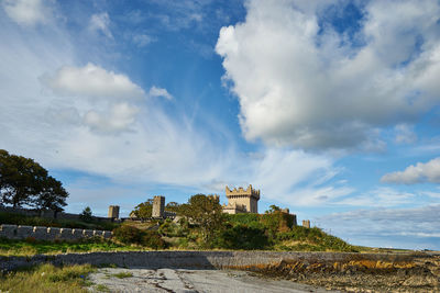 Low angle view of quintin castle against cloudy sky