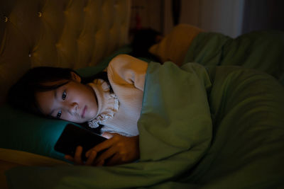 Girl using mobile phone while lying down on bed