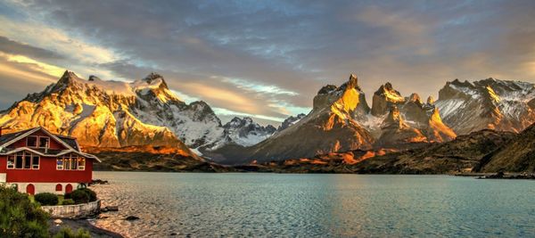 Scenic view of lake by mountains against sky during sunset