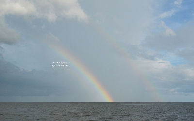 Scenic view of rainbow over sea against sky