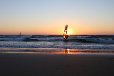 Silhouette of a person windsurfing at sunset
