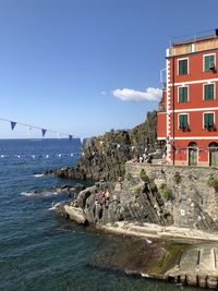 Buildings by sea against blue sky