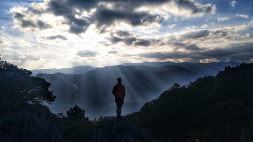 Rear view of man standing on mountain against sky