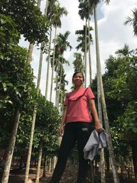 Portrait of young man standing on palm trees