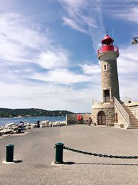 Lighthouse by sea against sky