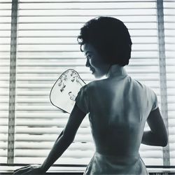 Side view of young woman looking through window