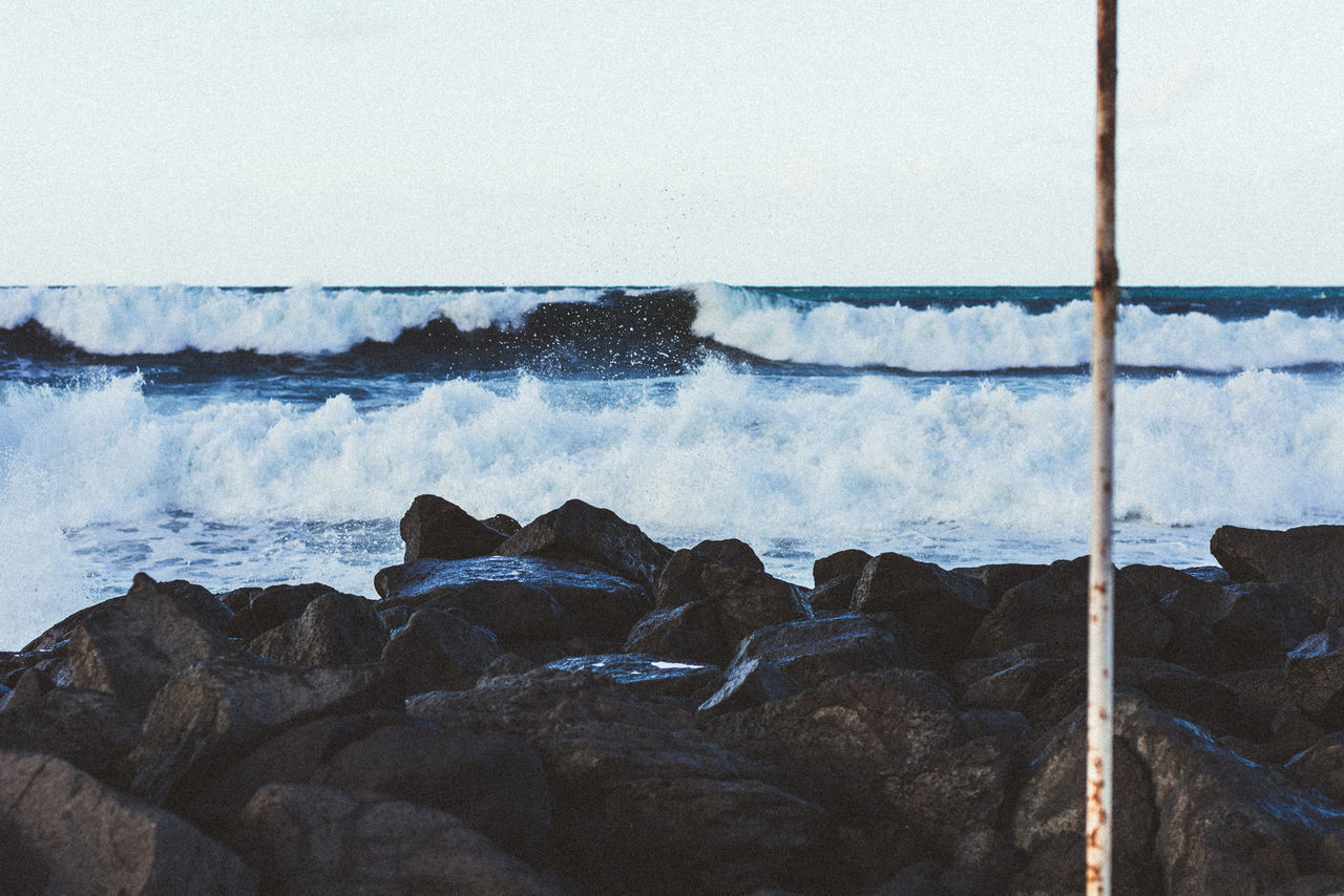 VIEW OF WAVES BREAKING AGAINST ROCKS