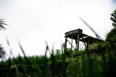 Low angle view of abandoned structure on field against sky