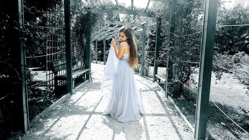 Young woman wearing dress standing at covered walkway