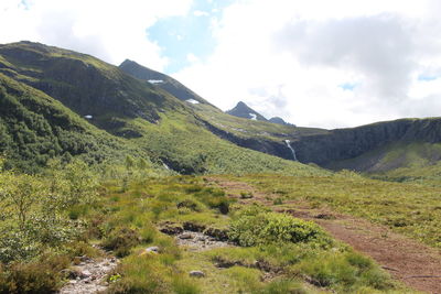 Scenic view of green landscape and mountains against sky