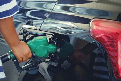 Cropped hand refueling car at gas station