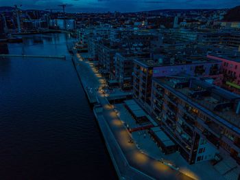 High angle view of illuminated city by buildings at dusk