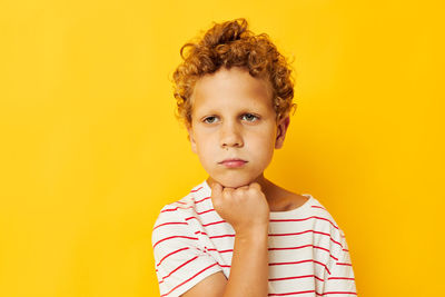 Boy looking away against yellow background