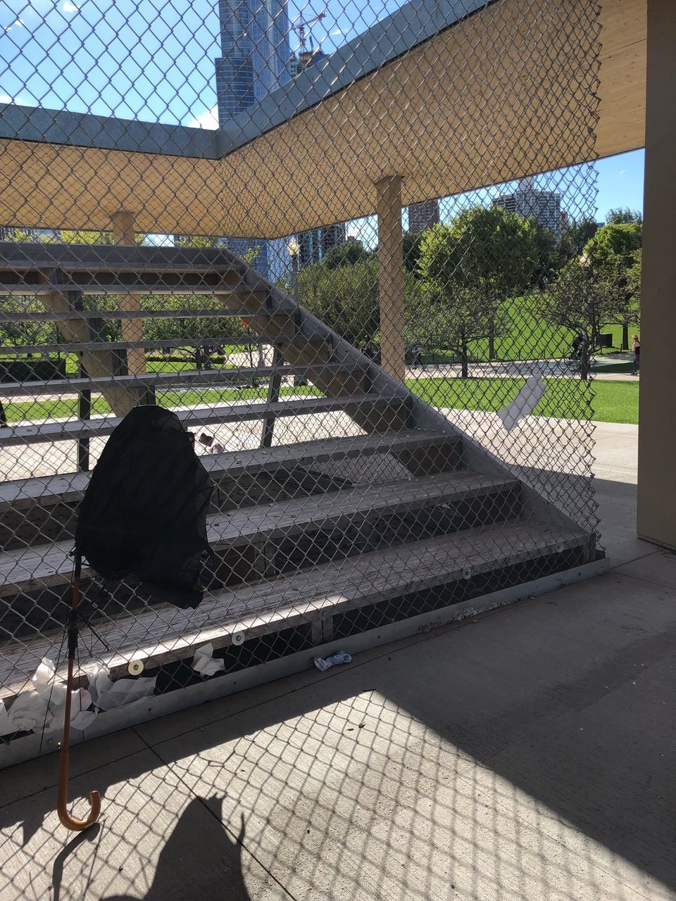 REAR VIEW OF PEOPLE SITTING ON METAL FENCE AGAINST TREES