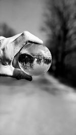 Close-up of hand holding crystal ball with reflection