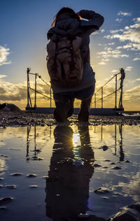 Man working on shore against sky during sunset