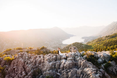 Man standing on rock against sky