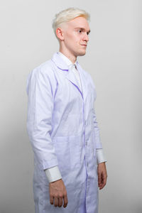 Doctor looking away while standing against white background