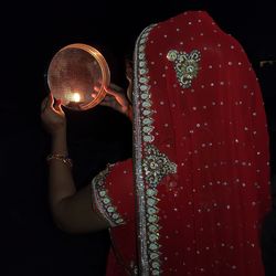 Woman in sari holding diya on strainer