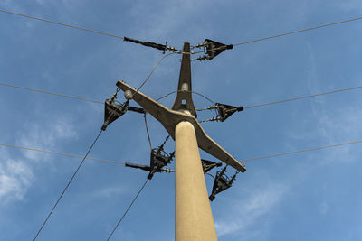 Low angle view of electricity pylon against blue sky